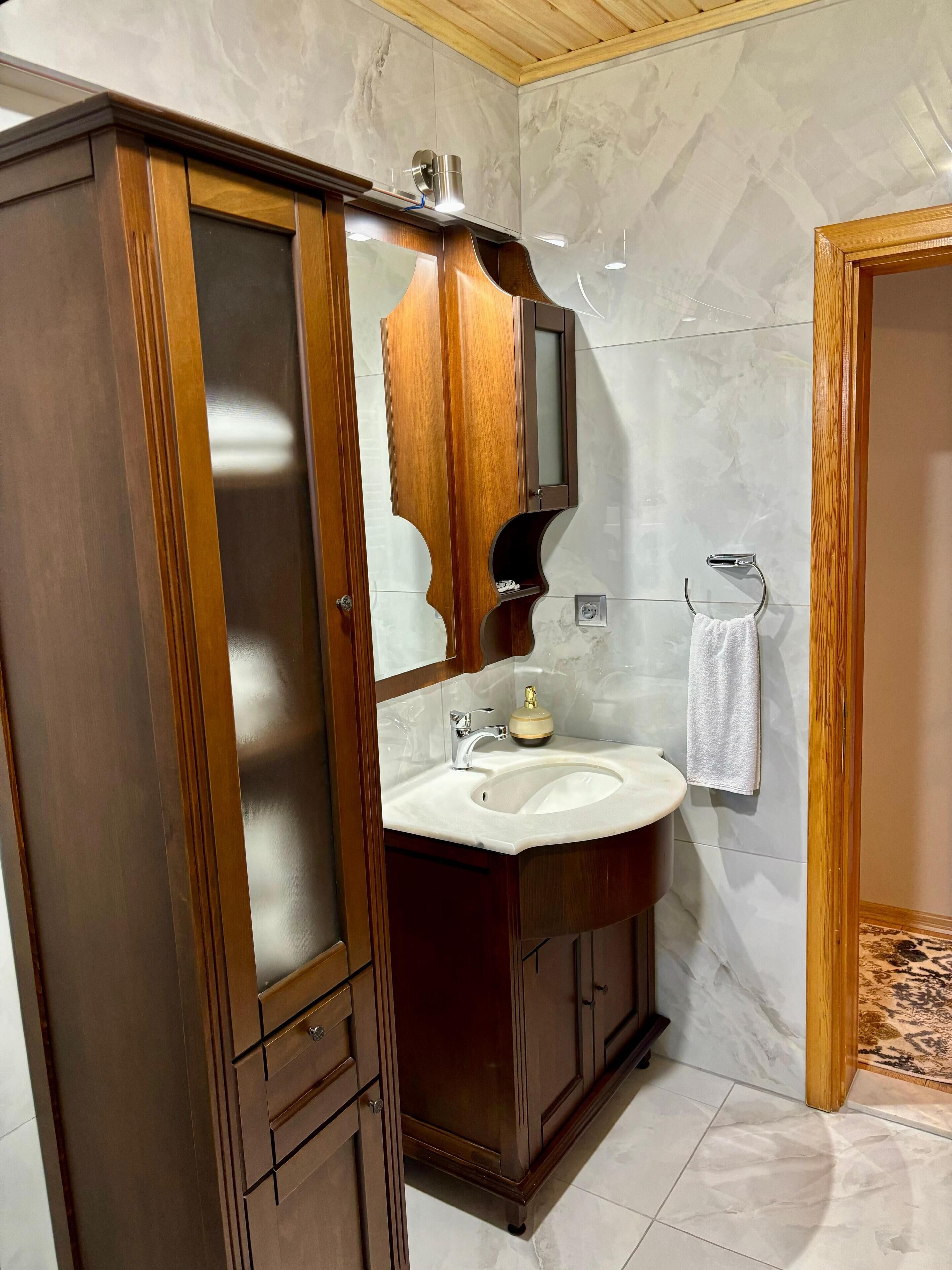 A bathroom with a wooden vanity, a sink, a mirror, and a towel rack.