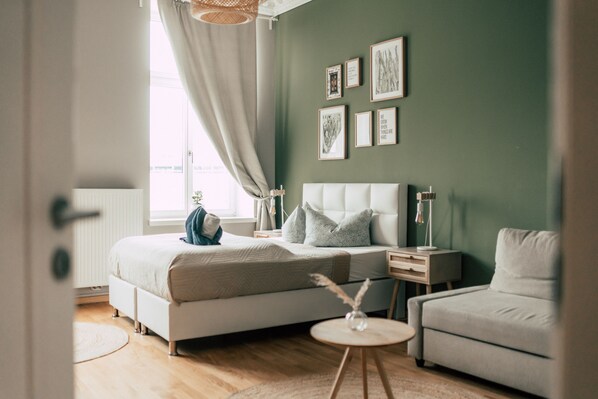 Une chambre à coucher comprenant un lit, des tables de chevet, une commode, une chaise et des tableaux encadrés accrochés au mur.