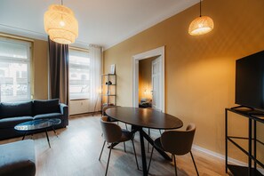 Una sala de estar moderna con una mesa redonda de comedor, un sofá y dos lámparas colgantes.