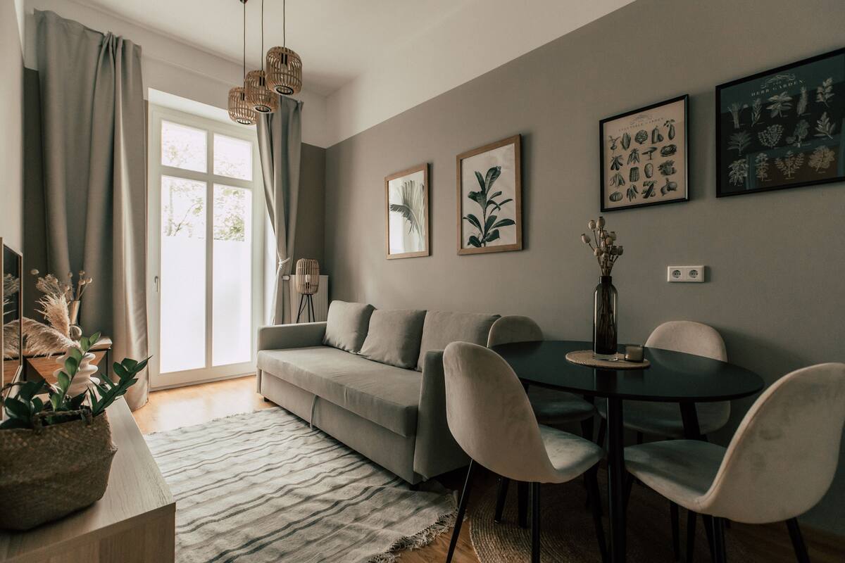 A modern living room with a sofa, dining table, chairs, and artwork on the walls.