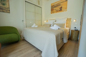 Quarto bem arrumado com uma cama grande, um sofá verde e um quadro na parede.