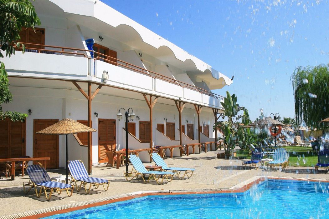 A poolside area with lounge chairs, a swimming pool, and a building with balconies.