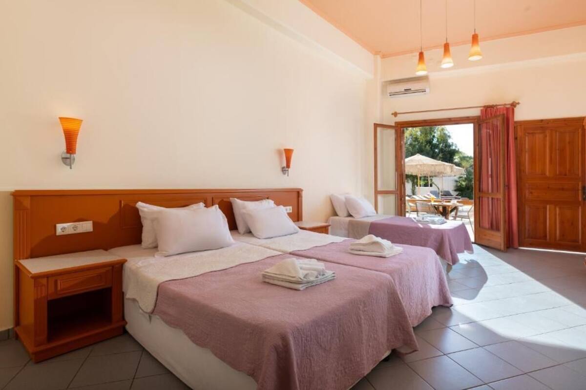 A hotel room with two beds, wooden headboards, and a small table with a chair.
