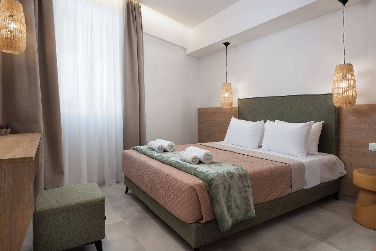 A modern hotel room with a bed, bedside tables, and a window with curtains.