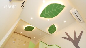 A modern interior with a staircase, green leaf-shaped wall decorations, and a white air conditioning unit. - Happiness Yes Inn (Luodong)