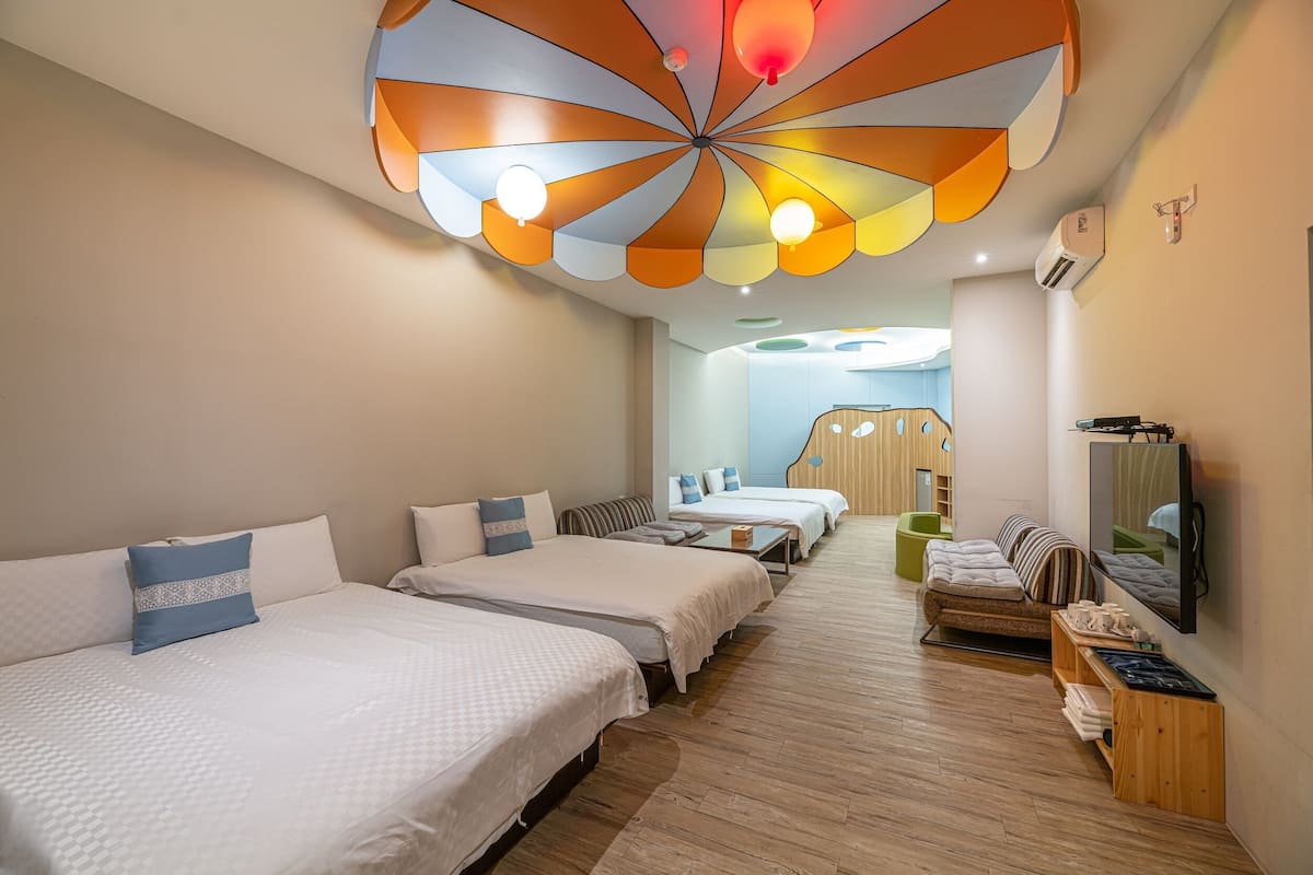 A hotel room with three beds, a television, and a ceiling light fixture.