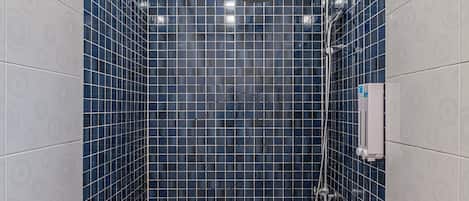 A small, tiled shower area with a colorful floor and blue-tiled walls.