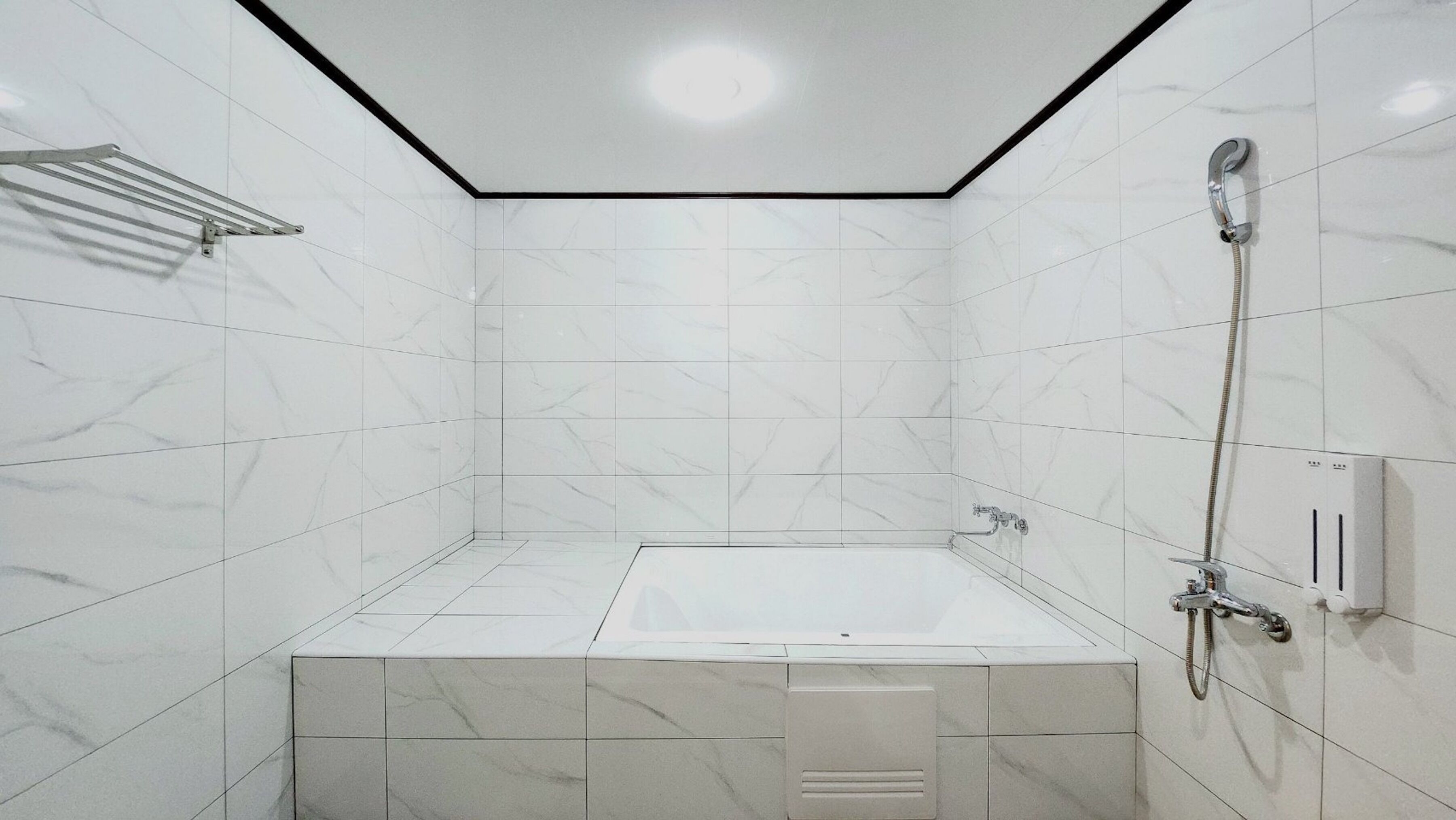 Un baño moderno con una bañera independiente, un cabezal de ducha de mano y un perchero para toallas.
