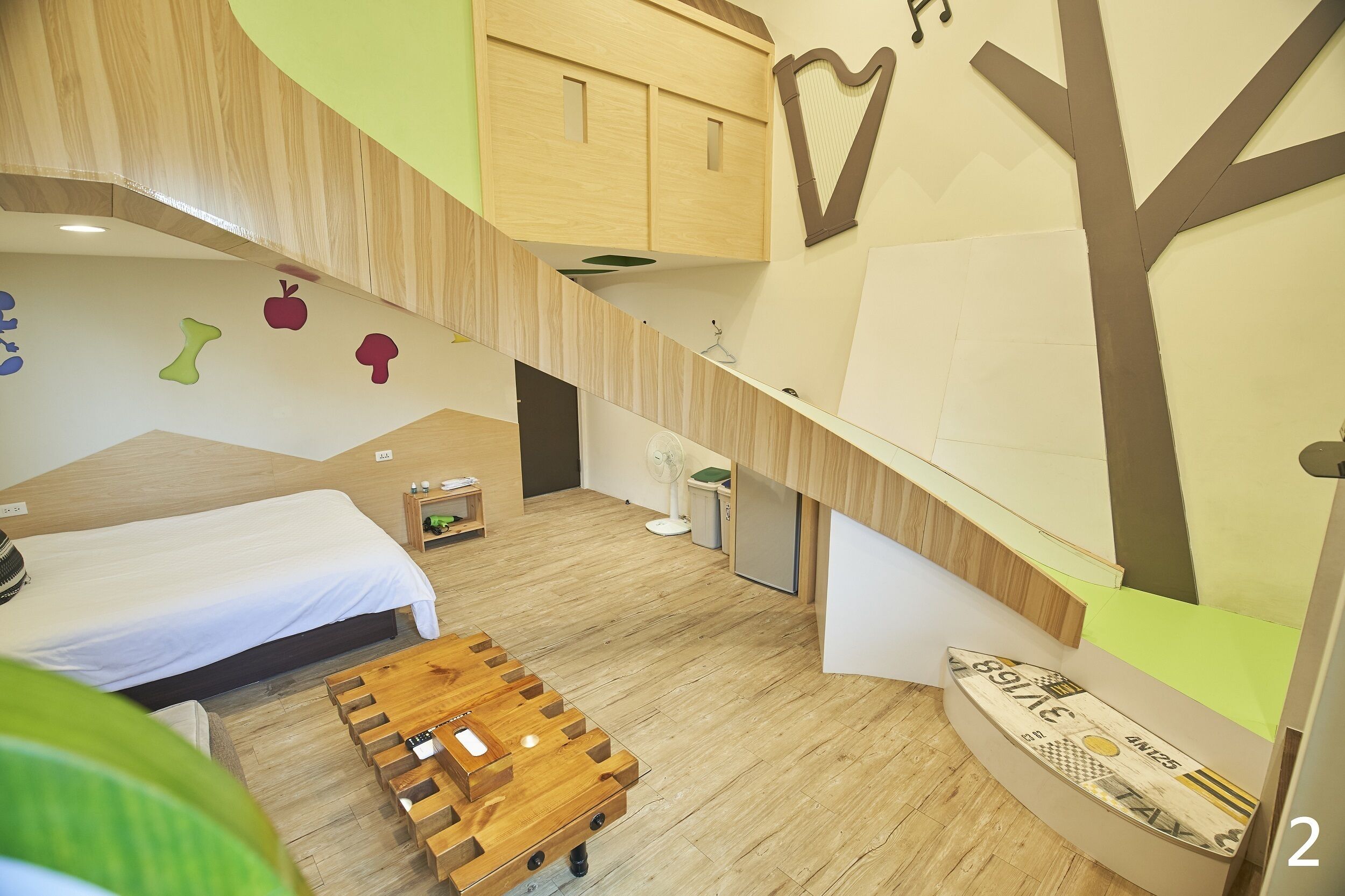 A modern room with a bed, a wooden table, and a wall with a tree design.