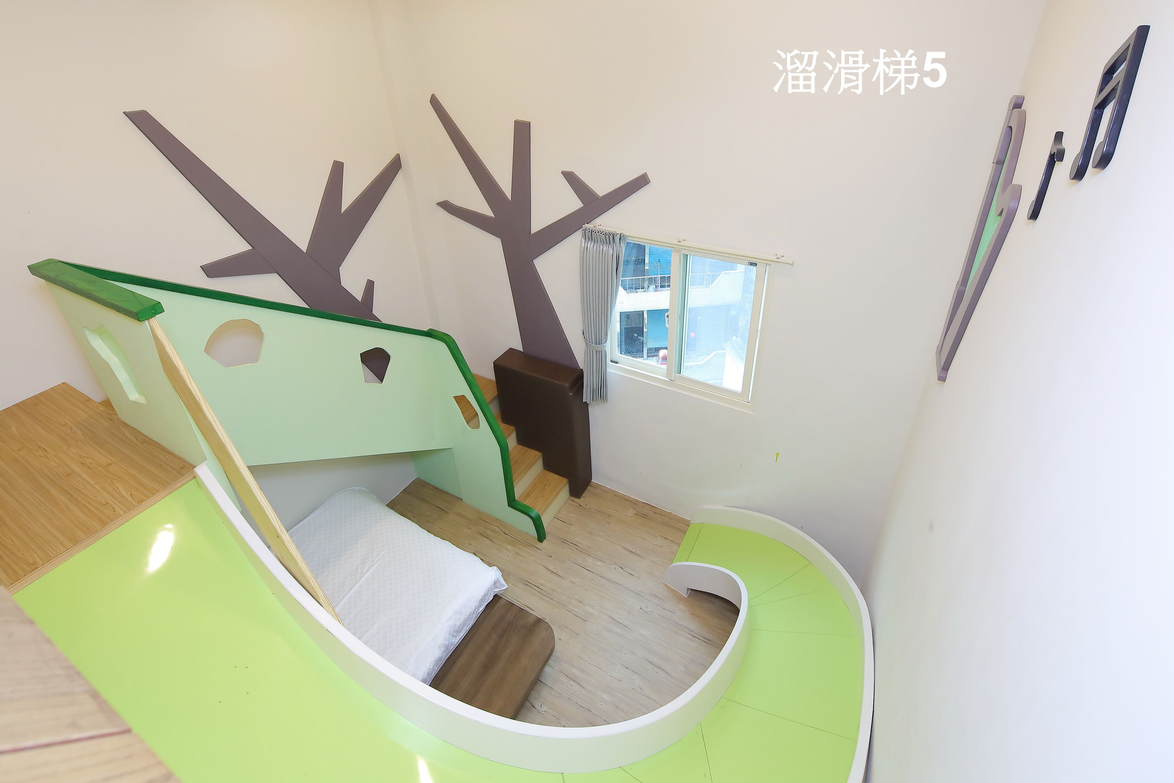 A child-friendly room with a bunk bed, a small desk, and a window with curtains.