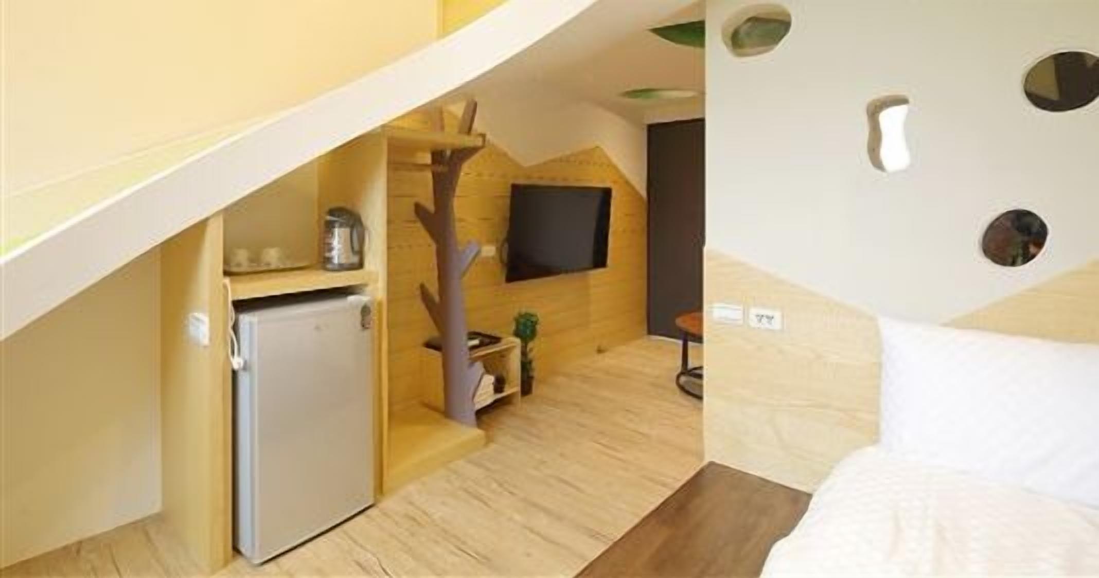 Ein kleines Hotelzimmer mit Küchenzeile, einer Sitzecke und einem an der Wand befestigten Fernseher.