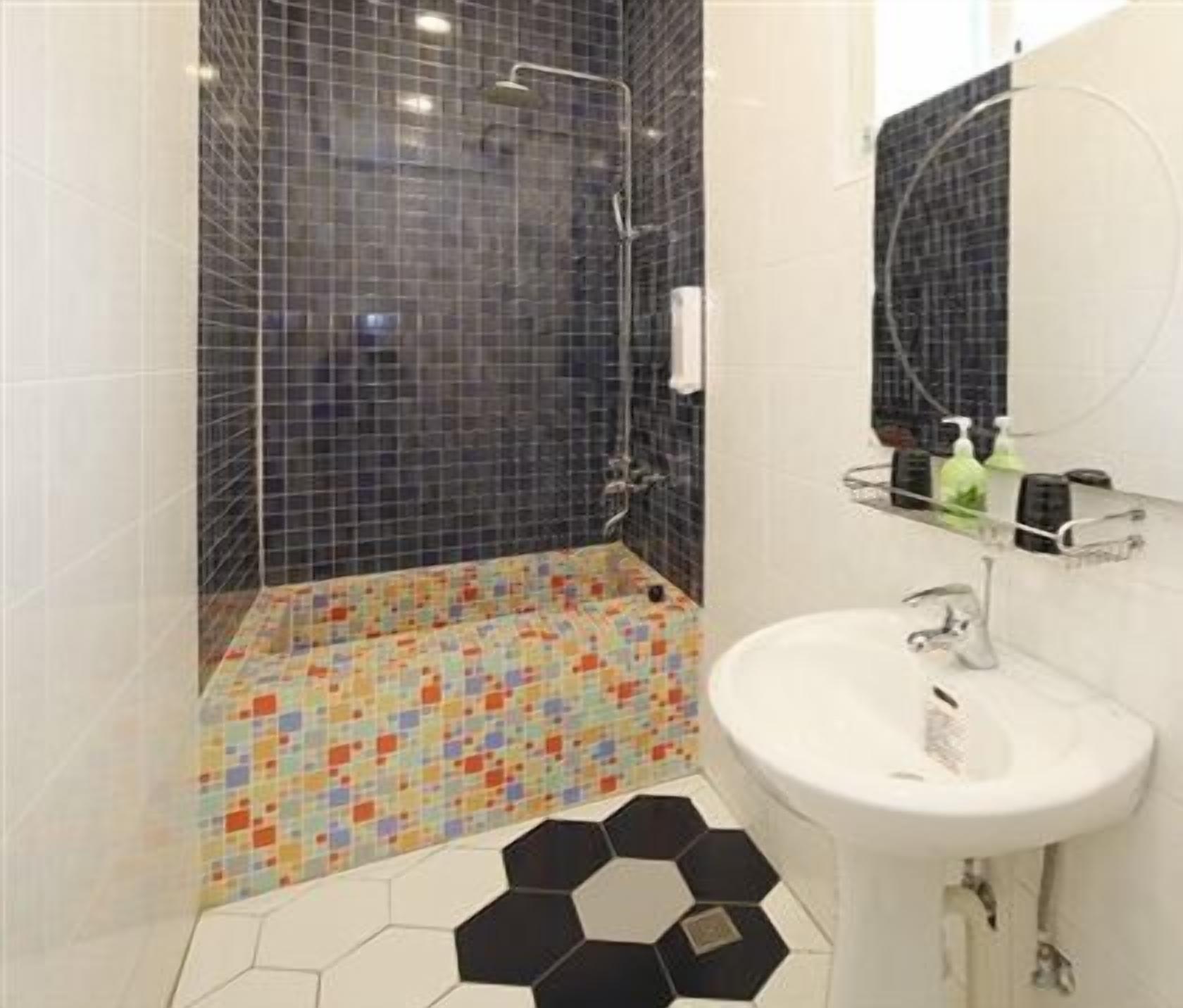 Een badkamer met een douche, wastafel en spiegel.