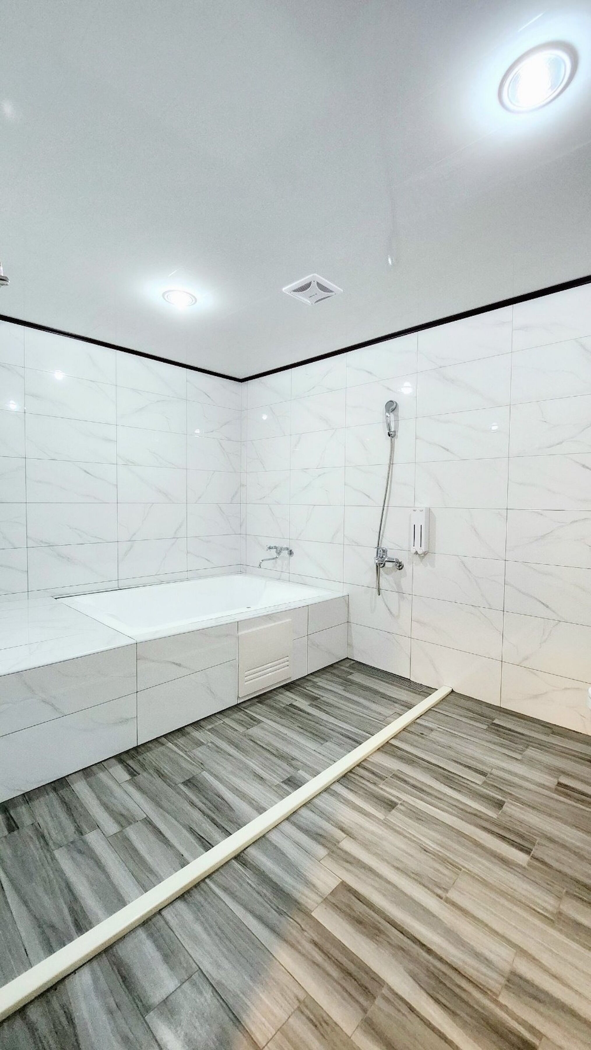 Une salle de bain moderne avec une grande baignoire, un espace douche et un plancher en bois.