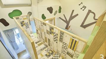 Una escalera con un suelo a cuadros y una pared decorada con formas abstractas y un diseño de árbol.