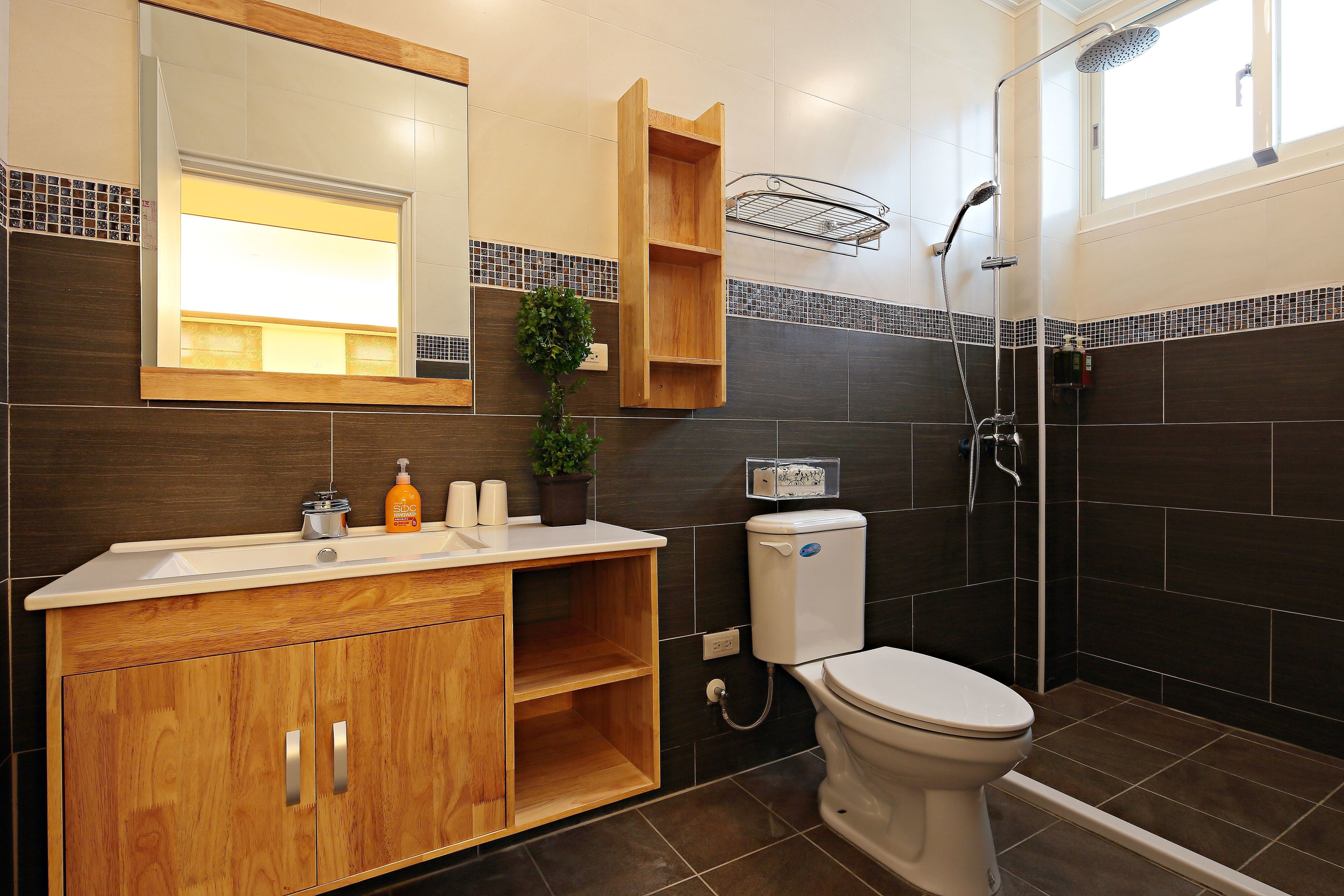 A modern bathroom with a wooden vanity, a toilet, a shower, and a mirror.