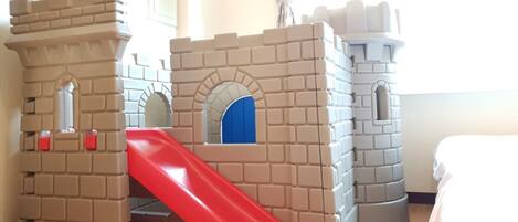 Zona de juegos infantiles con un tobogán y estructuras que recuerdan a un castillo.