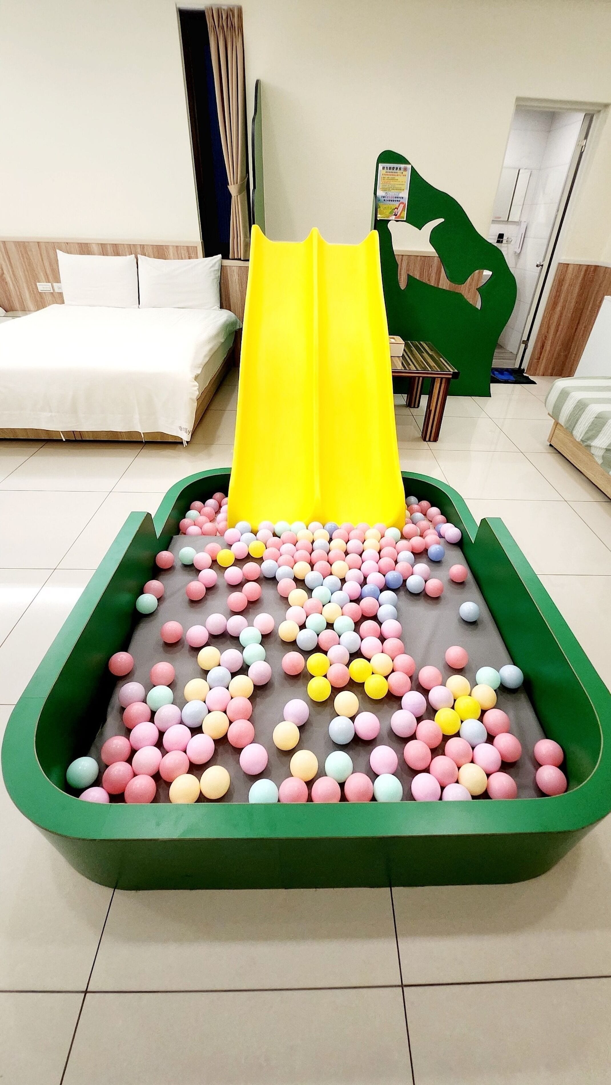 A play area with a yellow slide and a ball pit filled with multicolored balls.