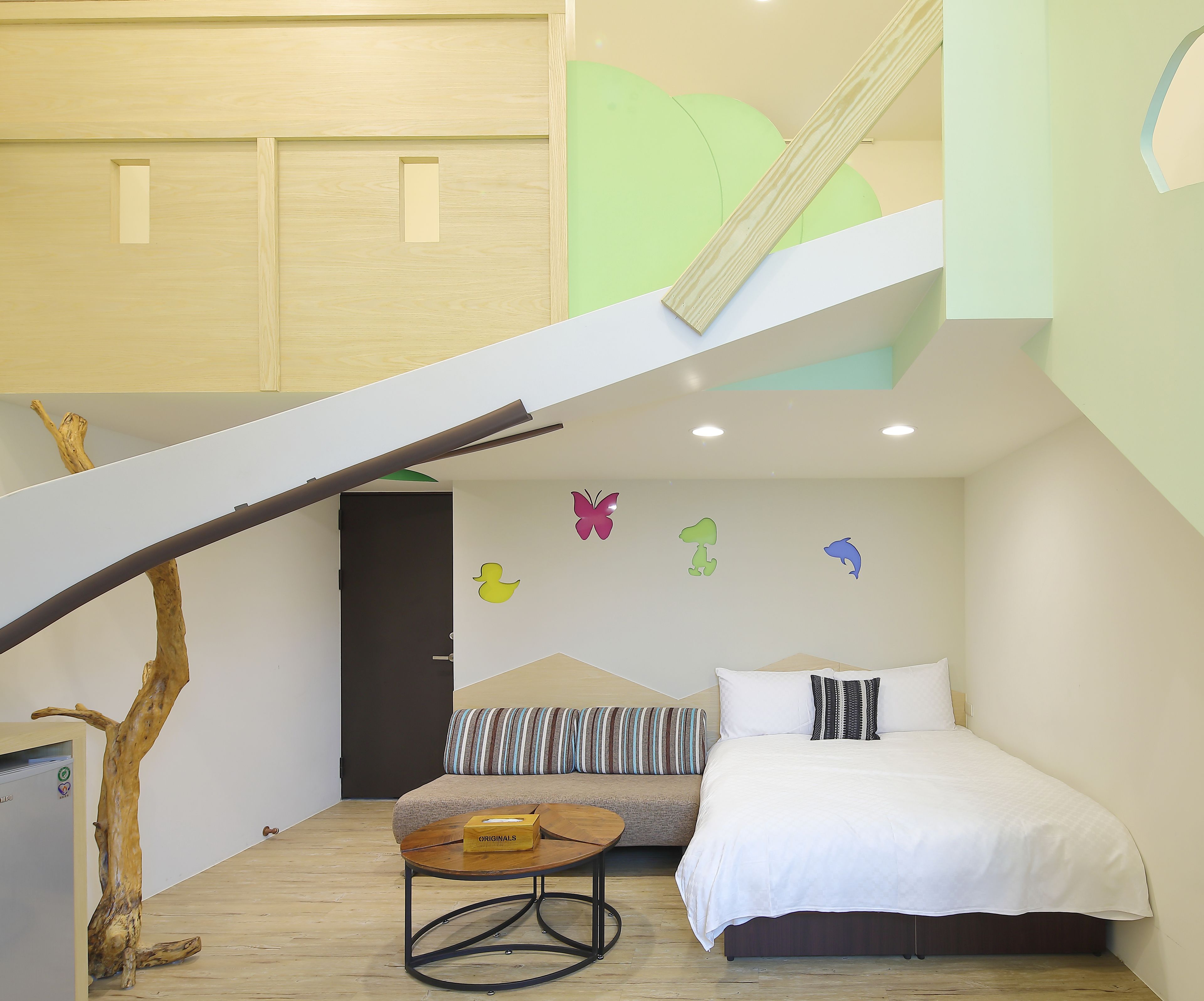 A bedroom with a bed, a sofa, a small table, and a staircase.