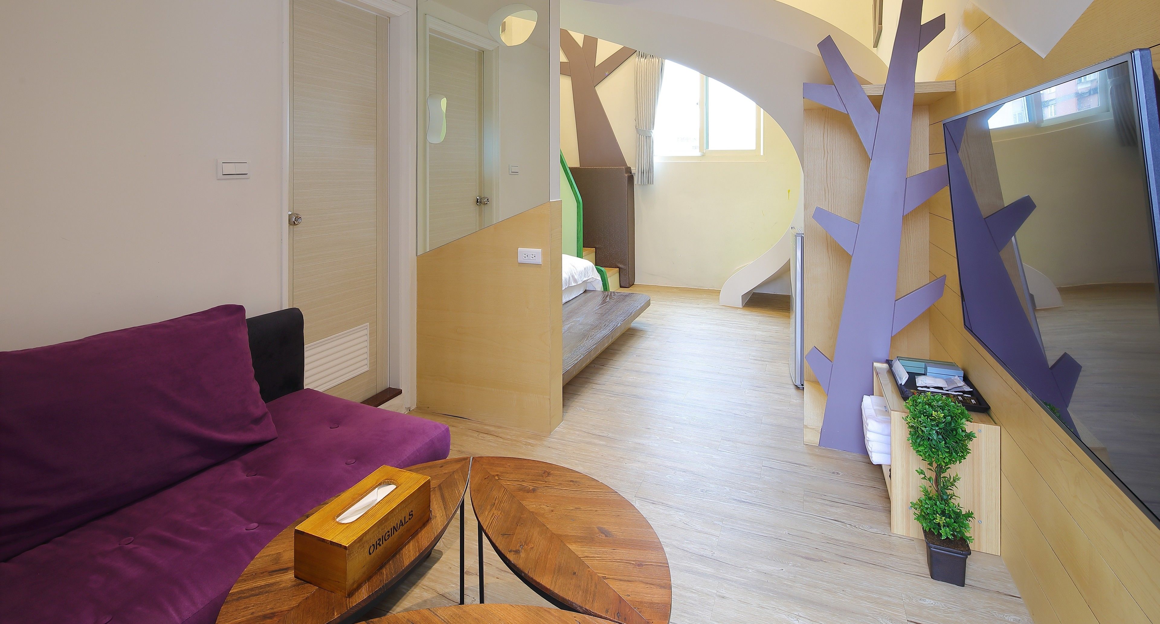 A modern living room with a purple sofa, a wooden coffee table, and a staircase leading to another level.