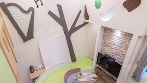A children's play area with a curved green floor, a whiteboard, and a brick wall with a fireplace. - Happiness Yes Inn (Luodong)