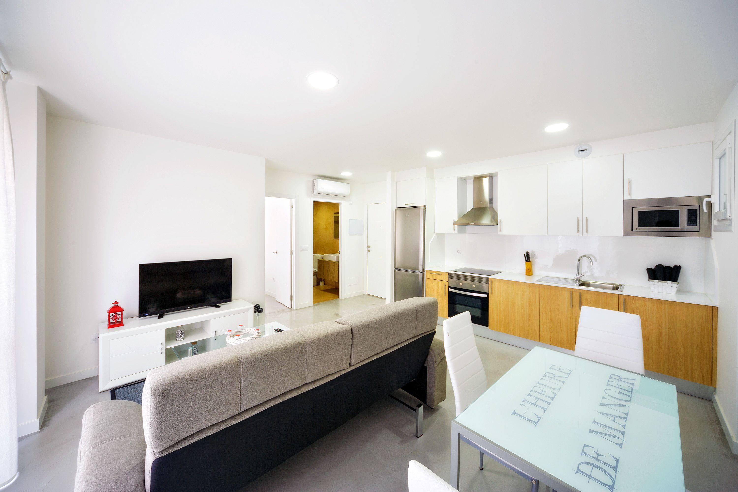 A modern apartment with a living area, kitchenette, and a dining table.