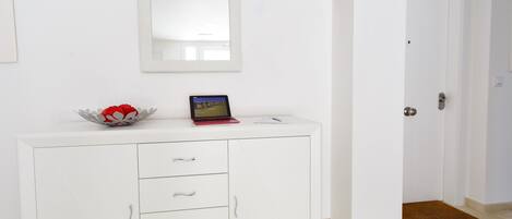 Un meuble blanc avec des tiroirs, et un ordinateur portable posé dessus.