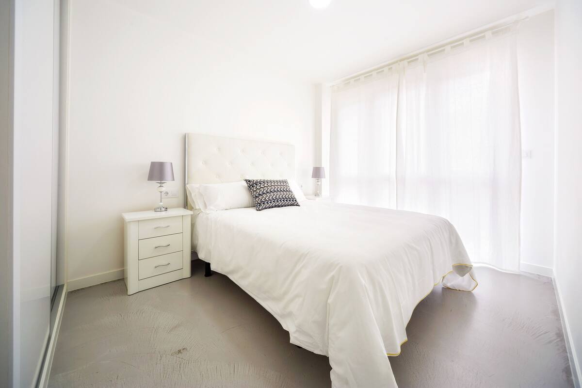 A bedroom with a bed, a nightstand, and a lamp.
