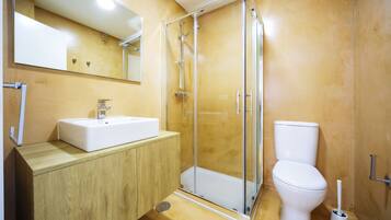 A bathroom with a glass-enclosed shower, a white sink, and a toilet.