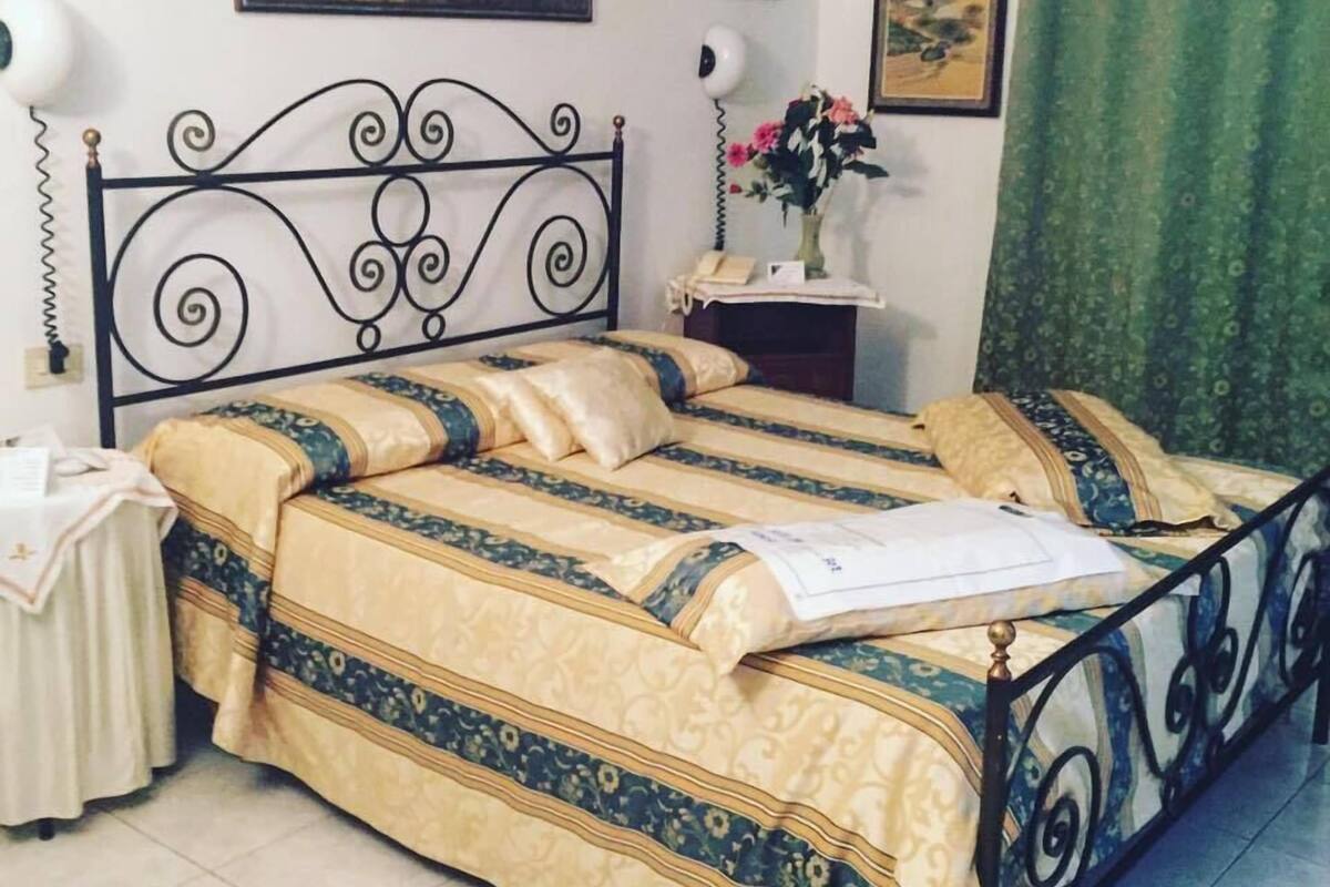 A room with a bed, a nightstand, a lamp, and a painting on the wall.