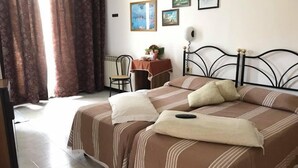 A bedroom with two beds, a chair, a table with a lamp, and framed pictures on the wall. - Hotel Ebe (Scarperia e San Piero)