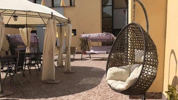 An outdoor patio area with a mosaic tile floor, a hanging chair, and a covered seating area with tables and chairs. - Hotel Ebe (Scarperia e San Piero)