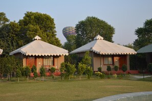Two bungalow-style buildings with pitched roofs and a hot air balloon in the background. - Lohana Village Resort (Pushkar)