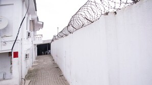 Une ruelle étroite, avec un mur blanc d’un côté et un immeuble de l’autre.