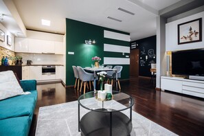 Uma sala de estar moderna com uma mesa de centro de vidro, sofá verde-água e uma área de jantar com cadeiras e mesa.