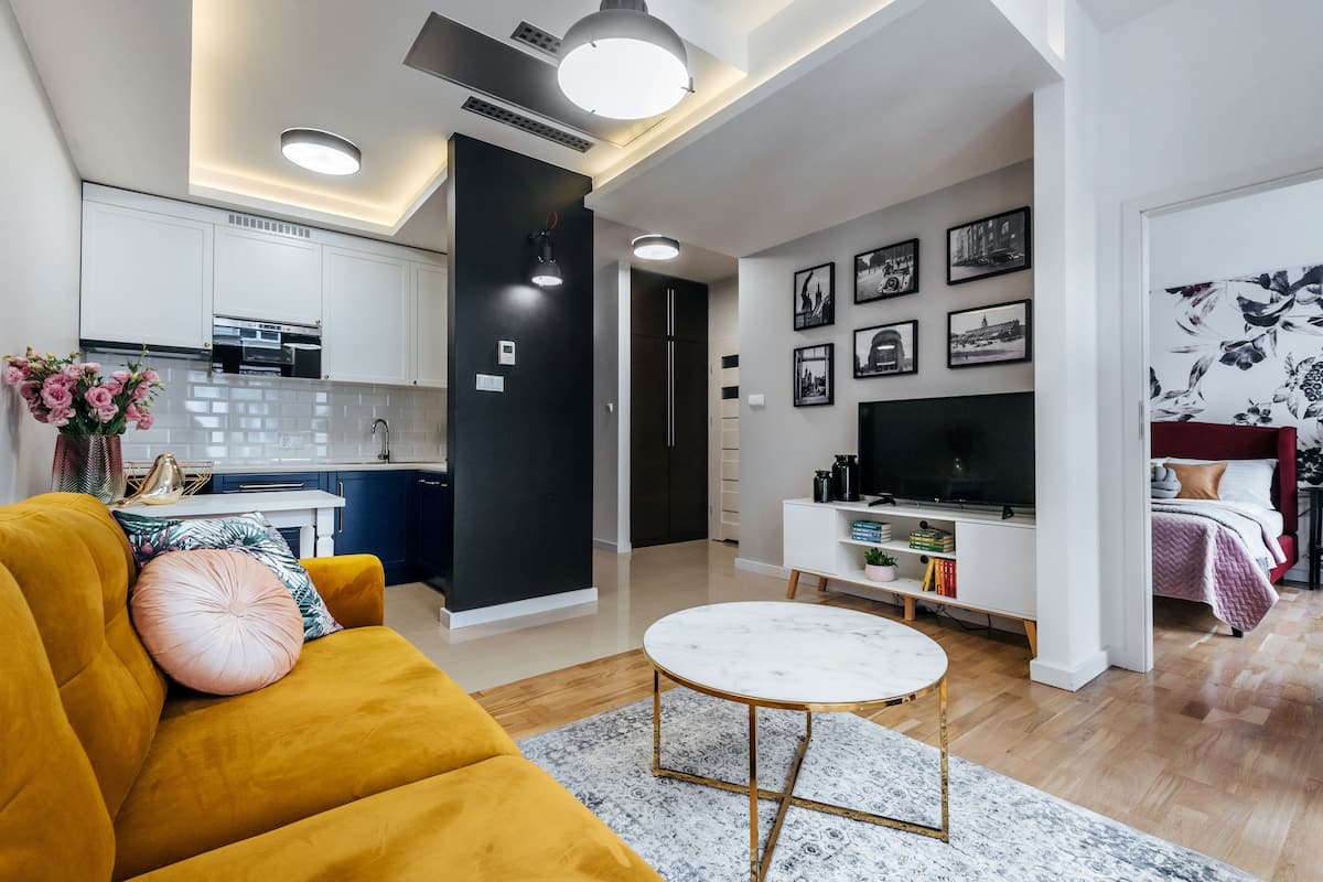 Un salon moderne avec un canapé jaune, une table basse ronde et un téléviseur.