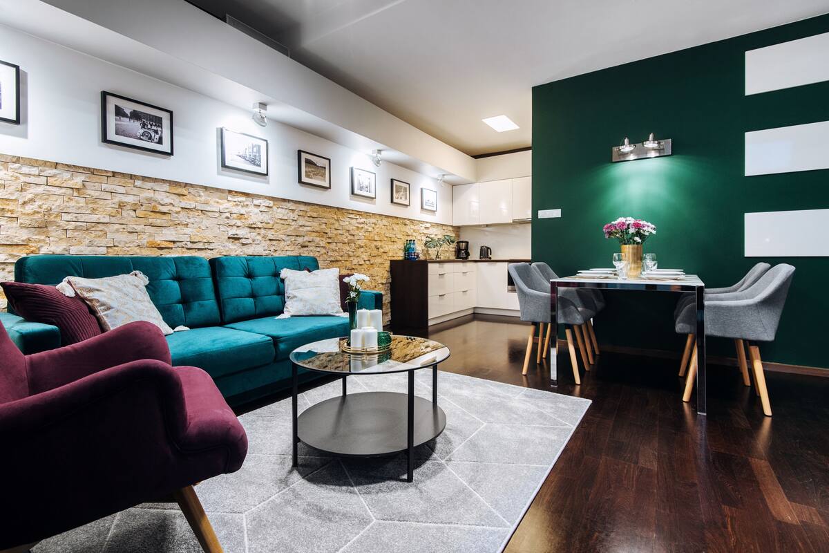 Un salon moderne avec un canapé de couleur turquoise, une table basse ronde et un coin repas comprenant une table et des chaises.