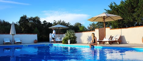Una piscina al aire libre, sombrillas, tumbonas