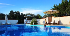 Een buitenzwembad, parasols bij het zwembad en ligstoelen