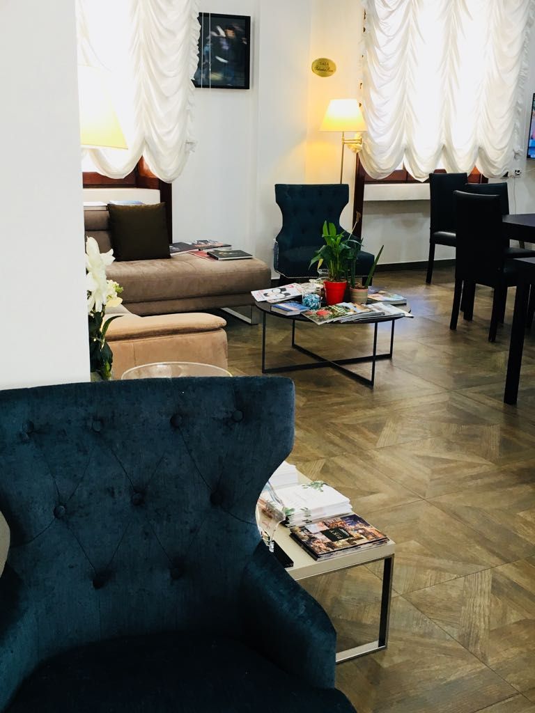 A living room with a sofa, a coffee table with magazines, a blue armchair, and a dining area with chairs.