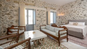 Una habitación con pared de piedra, cama, sofá, mesa y dos sillas.