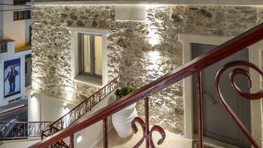 Un edificio moderno con fachada de piedra, un balcón con sombrilla blanca y barandilla roja.