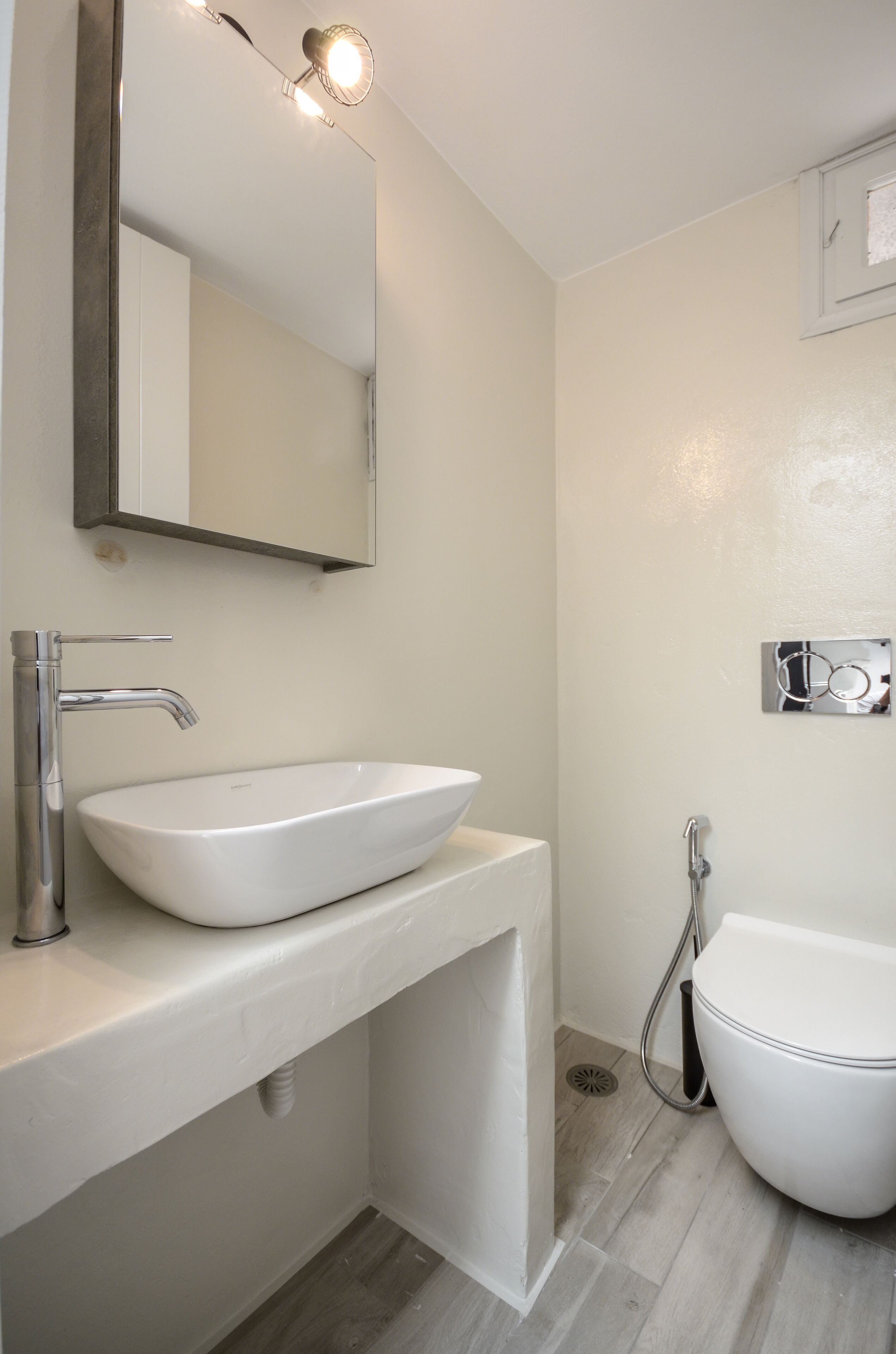 Een badkamer met een wit wastafel, een spiegel en een toilet.