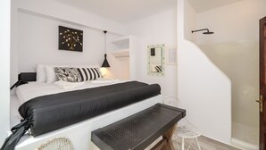 Un dormitorio moderno con cama, banco, silla y zona de ducha.