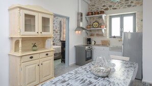Una cocina compacta con una mesa de mármol, horno empotrado y cafetera.