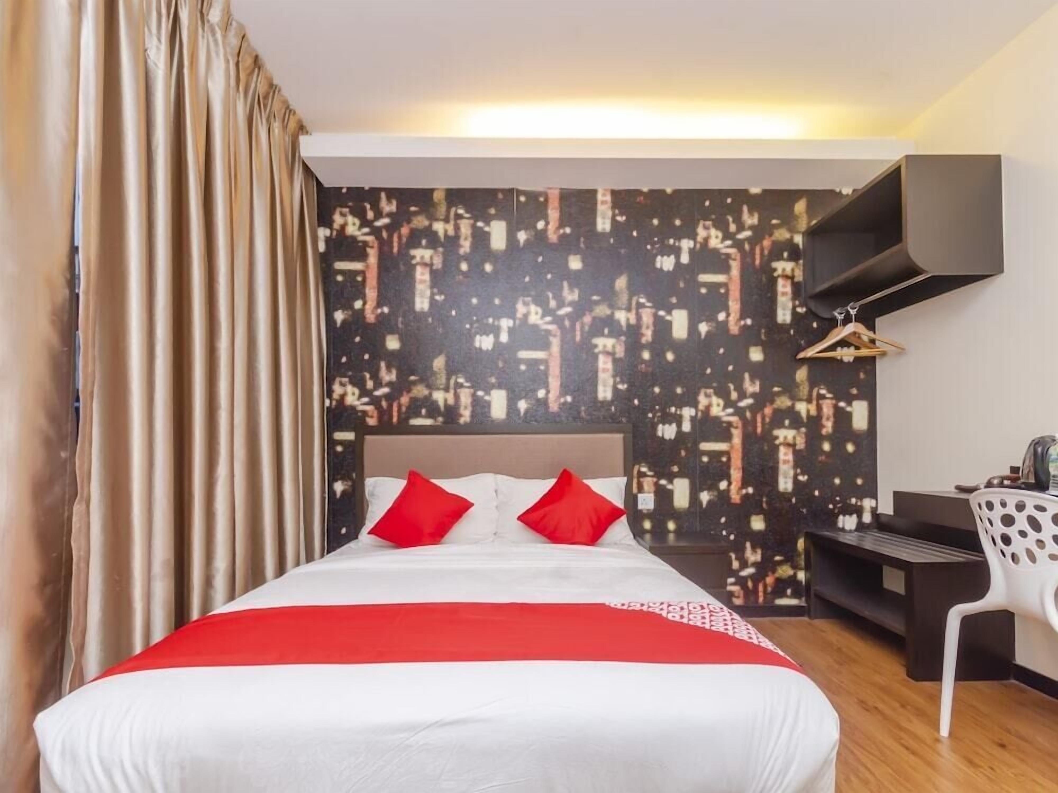 Hotellihuone, jossa on sänky, seinälle asennettu televisio ja työpöytä tuolilla.