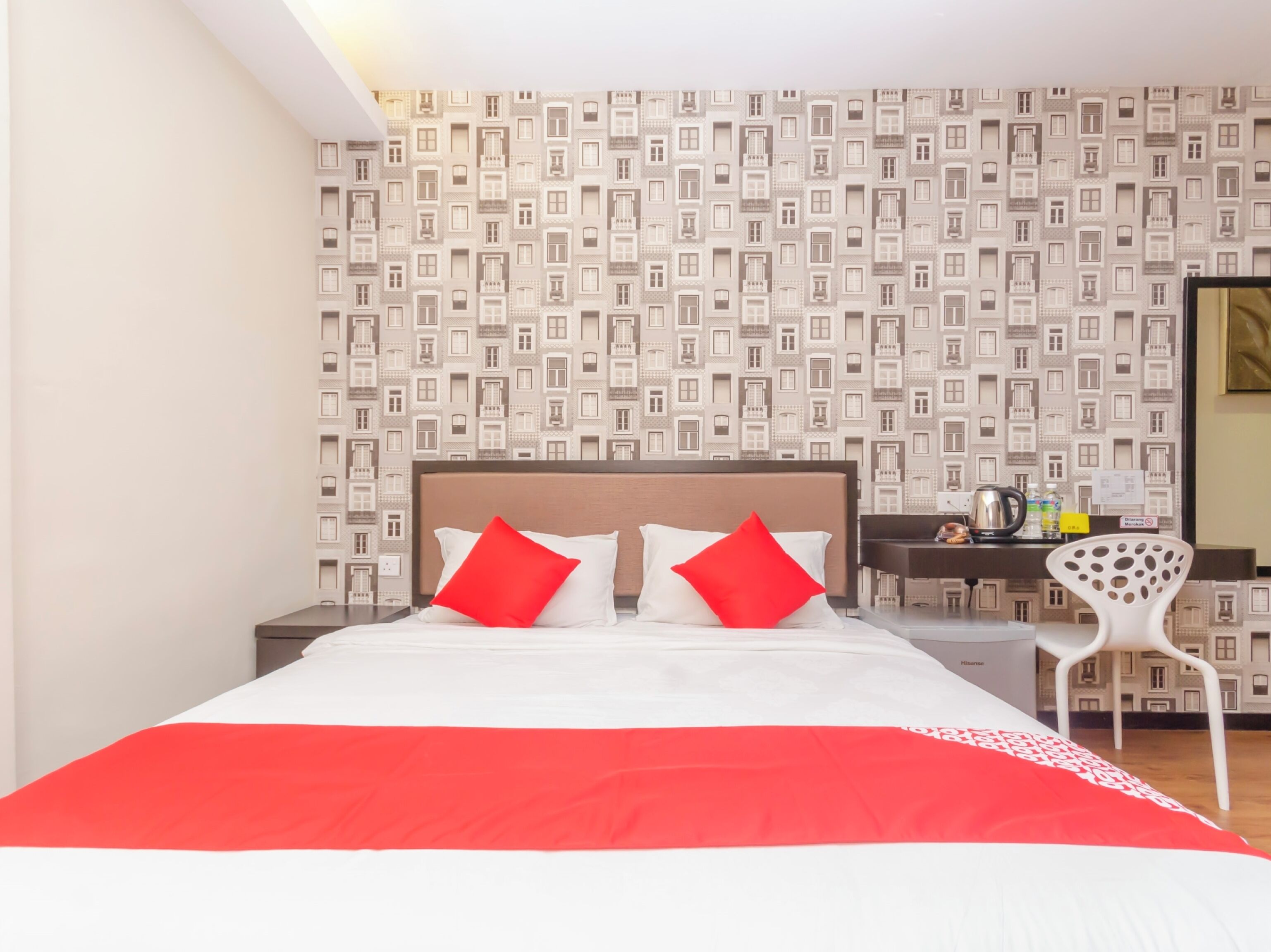 Habitación de hotel con cama, escritorio, silla y papel tapiz estampado.