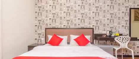 Habitación de hotel con cama, escritorio, silla y papel tapiz estampado.