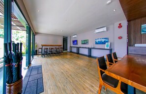 Une chambre d’hôtel moderne avec un plancher en bois, un coin repas avec une table et des chaises en bois, un comptoir de réception et des œuvres d’art accrochées aux murs.