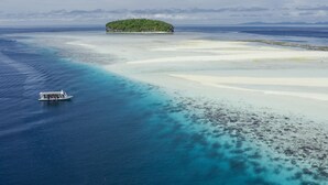 Vista aérea de una isla tropical con aguas turquesas cristalinas y playas de arena blanca.