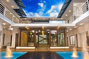 Un edificio moderno con un atrio de vidrio, una piscina y una escalera.